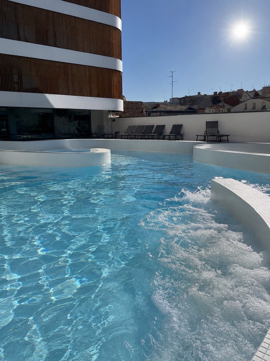 Jacuzzi na tarasie, w tle budynek resortu