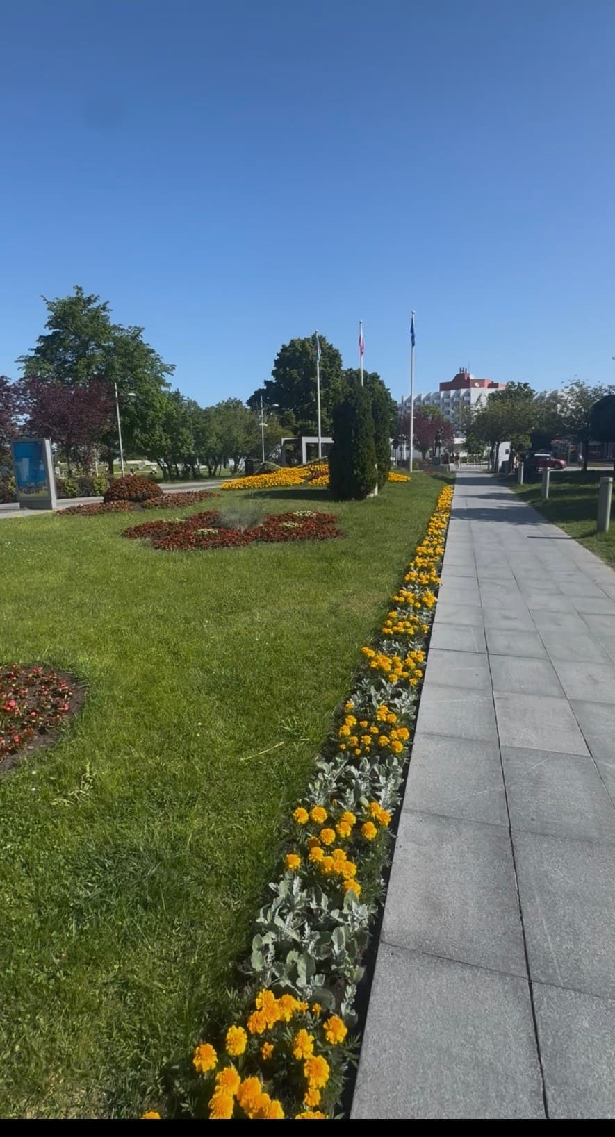 Rabaty kwiatowe w parku, w tle budynek resortu